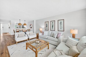 A living room with a sofa, chairs, a coffee table, and framed botanical prints on the wall.