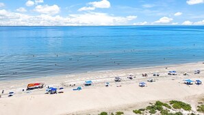 A beach with clear blue water, a sandy shore, and several beach umbrellas. - Stunning ocean view condo in Sanibel, 2BR, 2BA, perfect for up to 6 guests. (Sanibel)