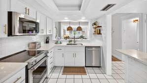 A modern kitchen with white cabinetry, stainless steel appliances, and pendant lighting. - Stunning ocean view condo in Sanibel, 2BR, 2BA, perfect for up to 6 guests. (Sanibel)