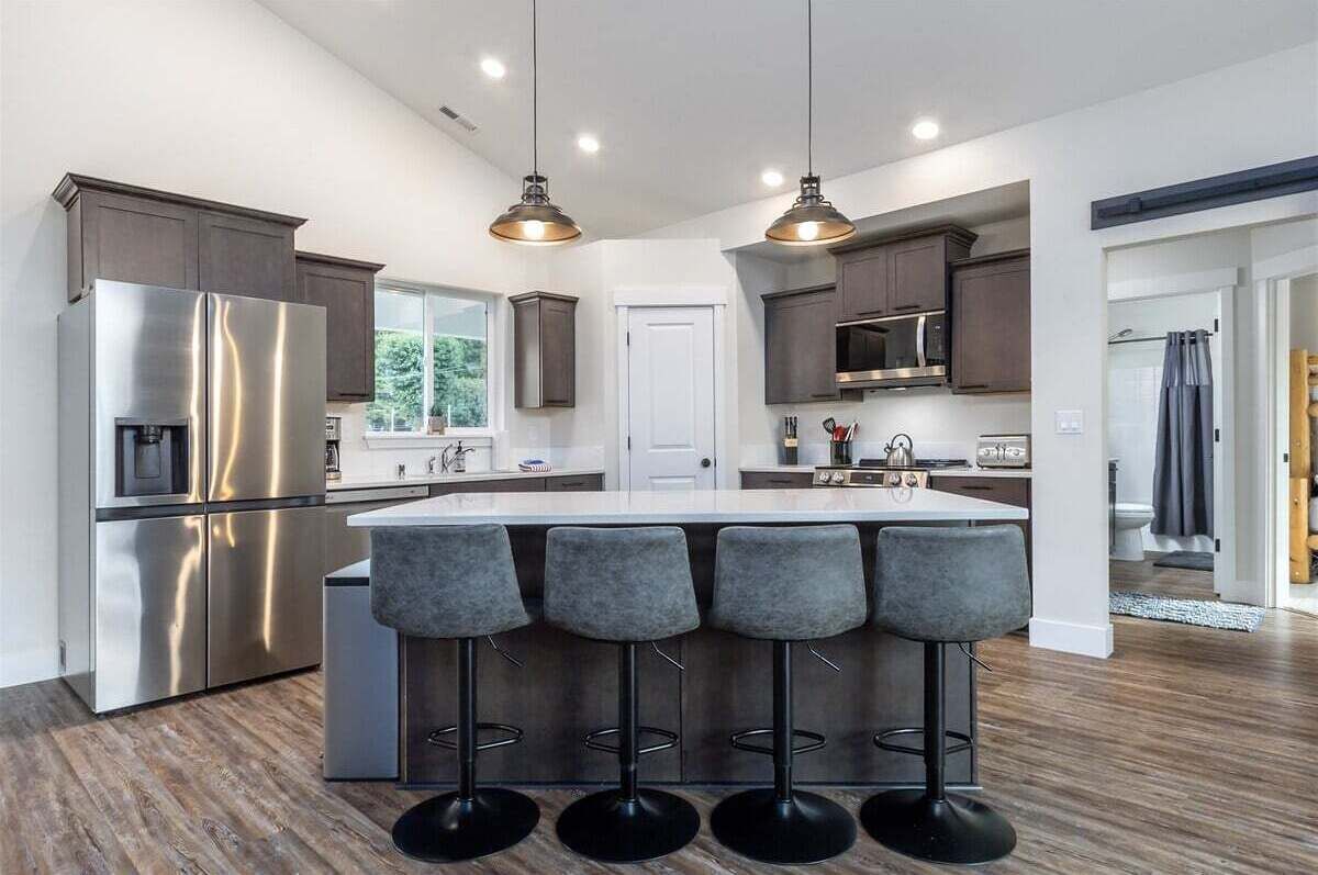 A modern kitchen with a stainless steel refrigerator, a microwave, and a large island with bar stools.