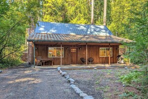 A rustic cabin with a metal roof, wooden walls, and a gravel driveway. - Alpine Drift | Hot Tub, Pet Friendly, Wifi (Packwood)