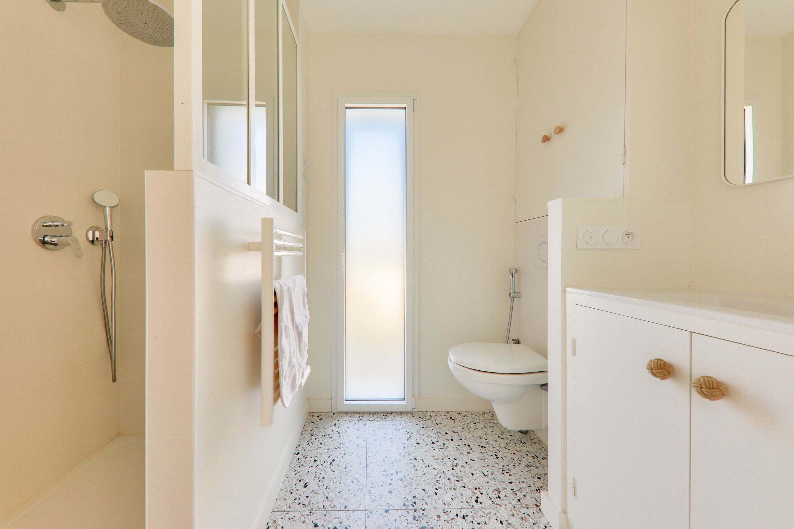 A bathroom with a shower, toilet, and a cabinet.
