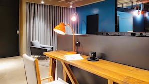 A modern room with a wooden desk, a black chair, a grey sofa, and a large window with curtains. - w Elegant Loft w Amazing Deco in Poblado (Medellín)