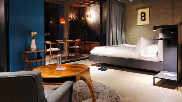 A modern bedroom with a bed, a wooden coffee table, a chair, and a small table with a vase. - w Elegant Loft w Amazing Deco in Poblado (Medellín)