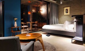 A modern bedroom with a bed, a wooden coffee table, a chair, and a small table with a vase. - w Elegant Loft w Amazing Deco in Poblado (Medellín)