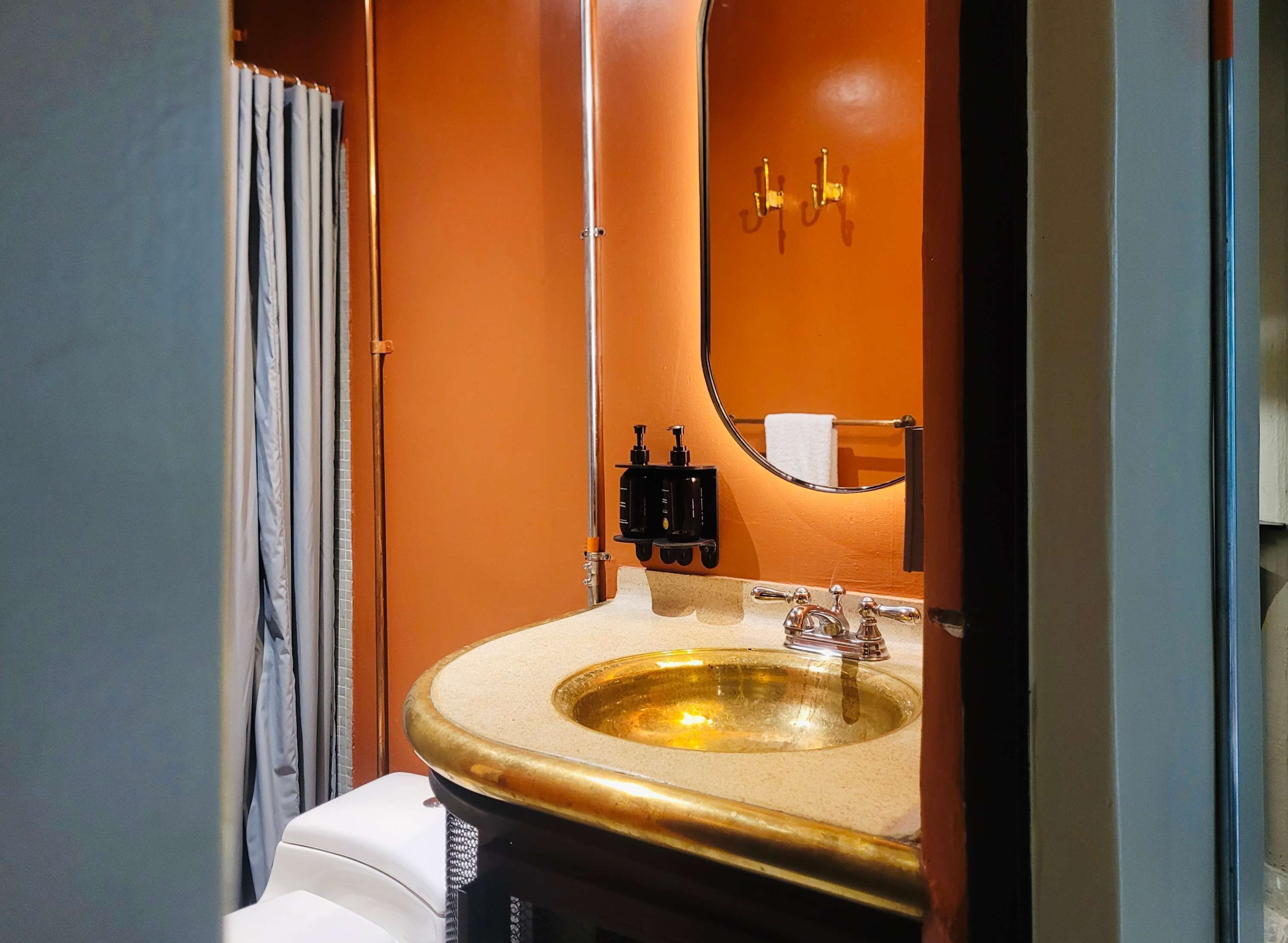 Ein Badezimmer mit einem goldfarbenen Waschbecken, einem Spiegel und einem Handtuchhalter.