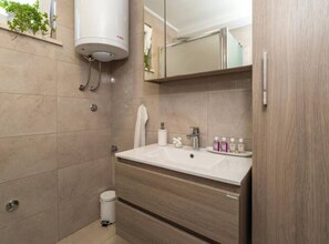 A modern bathroom with a large mirror, a sink, and a toilet.