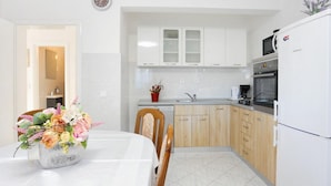 A modern kitchen with white cabinets, a microwave, a refrigerator, and a sink. - Holiday Home Nada Rogoznica (Rogoznica)