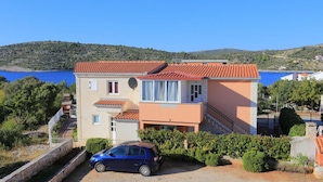 A two-story building with a red-tiled roof, a satellite dish, and a car parked in front. - Holiday Home Nada Rogoznica (Rogoznica)
