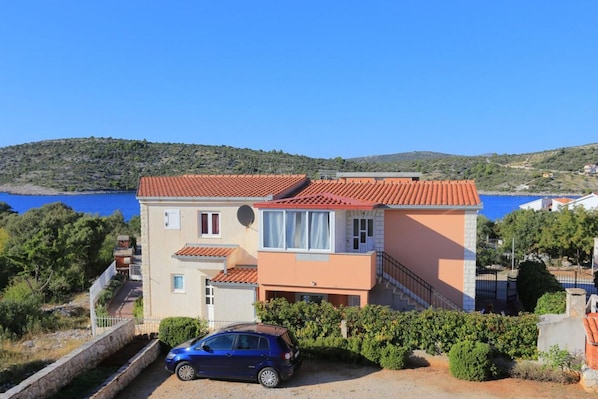 A two-story building with a red-tiled roof, a satellite dish, and a car parked in front. - Holiday Home Nada Rogoznica (Rogoznica)