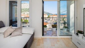 A bedroom with a bed, a sliding glass door to a balcony, and an air conditioning unit. - Omis River & Sea Escape (Omis)