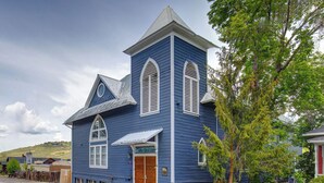 Eine blaue Kirche mit weißem Kirchturm, Holztüren und einer kleinen Veranda.