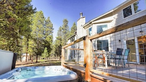 Un bain à remous à l’extérieur d’une maison, avec une terrasse en bois et un patio clos.