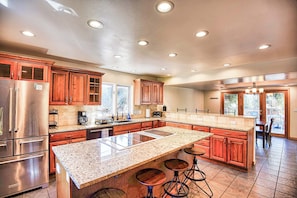 A spacious kitchen with granite countertops, stainless steel appliances, and wooden cabinets.