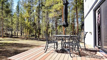 A deck with a table and chairs, surrounded by a forest.