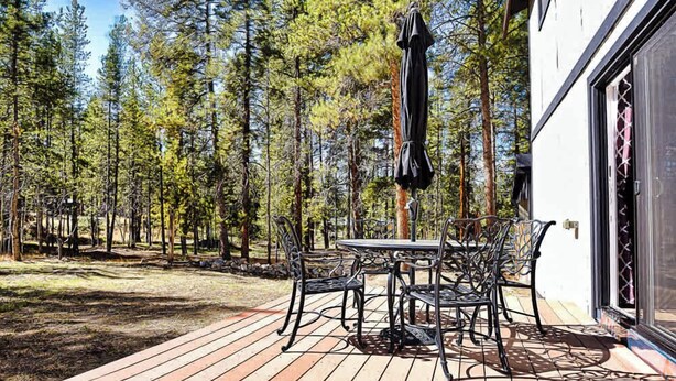 En terrass med ett bord och stolar, omgiven av en skog.