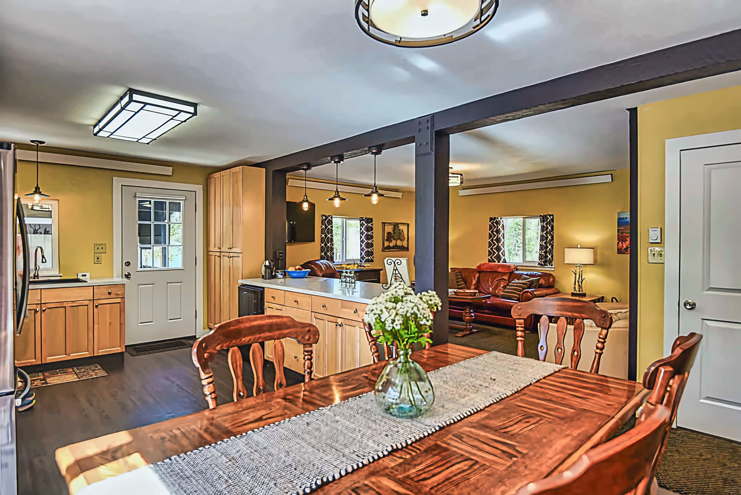 A dining area with a wooden table, chairs, and a vase of flowers.