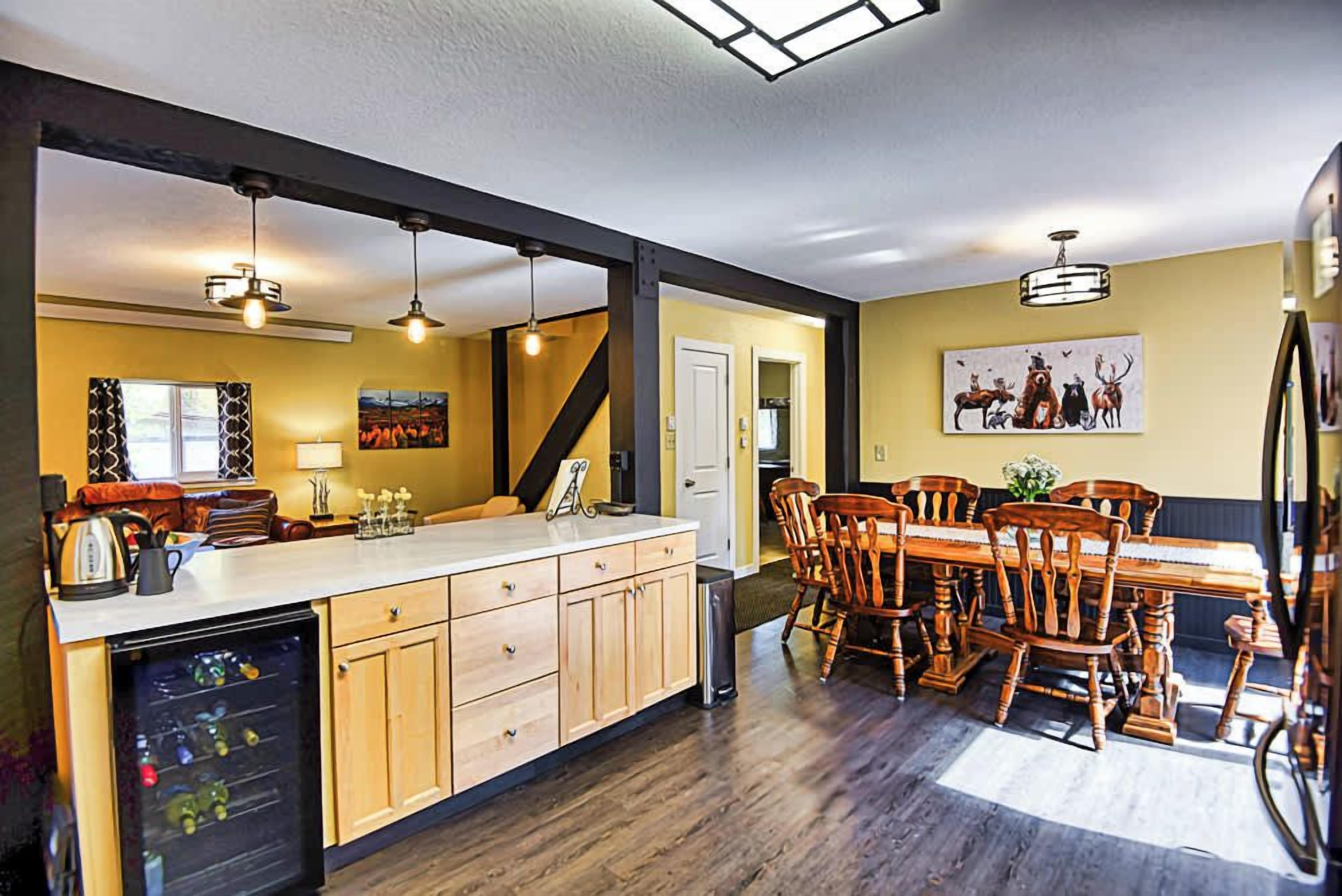 A kitchen with wooden cabinets, a dining area with a wooden table and chairs, and pendant lighting.