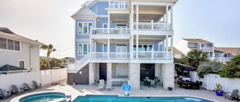 Una casa de varios pisos con piscina, mobiliario de exterior y terraza cubierta.