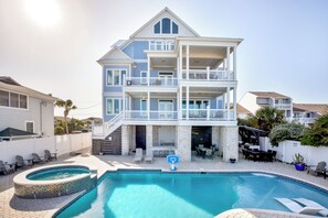 A multi-story house with a swimming pool, outdoor seating, and a covered patio.