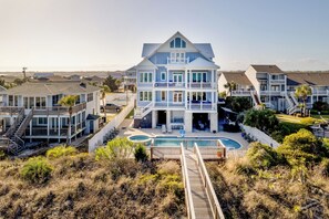 A multi-story beachfront property with a swimming pool, multiple balconies, and a covered outdoor area.
