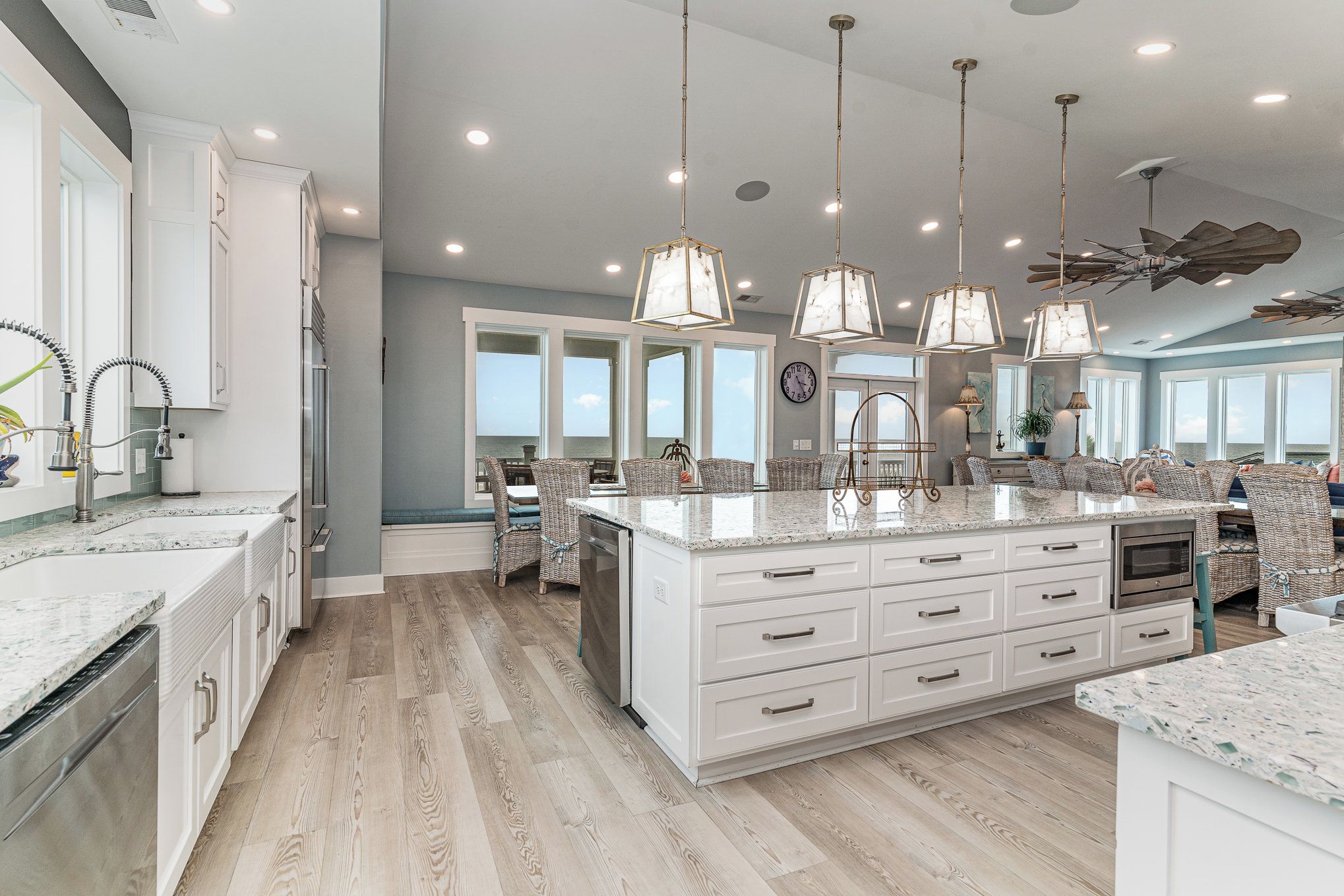 A spacious kitchen with white cabinetry, a large island, and pendant lighting.