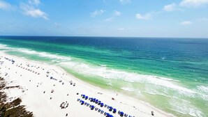 A beach with white sand, clear turquoise water, and a clear sky.