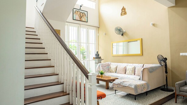 A staircase leading to a living area with a sofa, a fan, and a mirror on the wall.