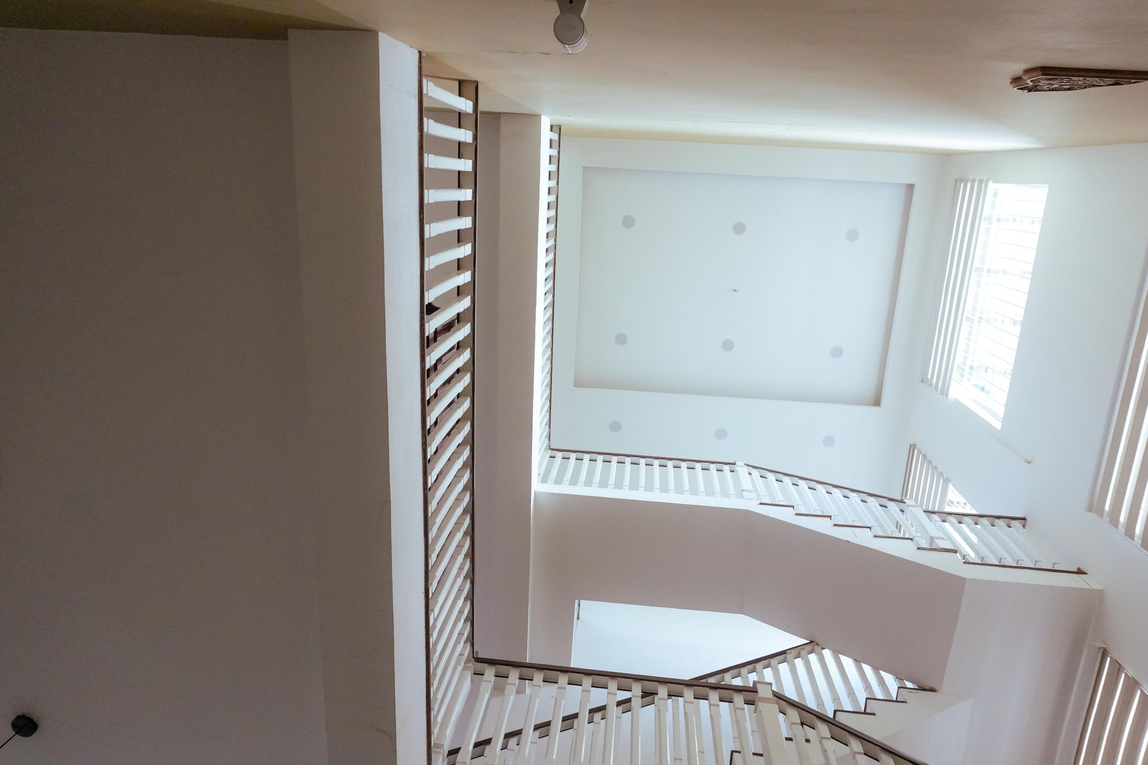 A multi-level interior with a white staircase and a ceiling with a grid pattern.