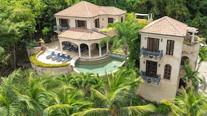 Ein geräumiges Haus mit Swimmingpool, mehreren Balkonen und üppiger Bepflanzung.