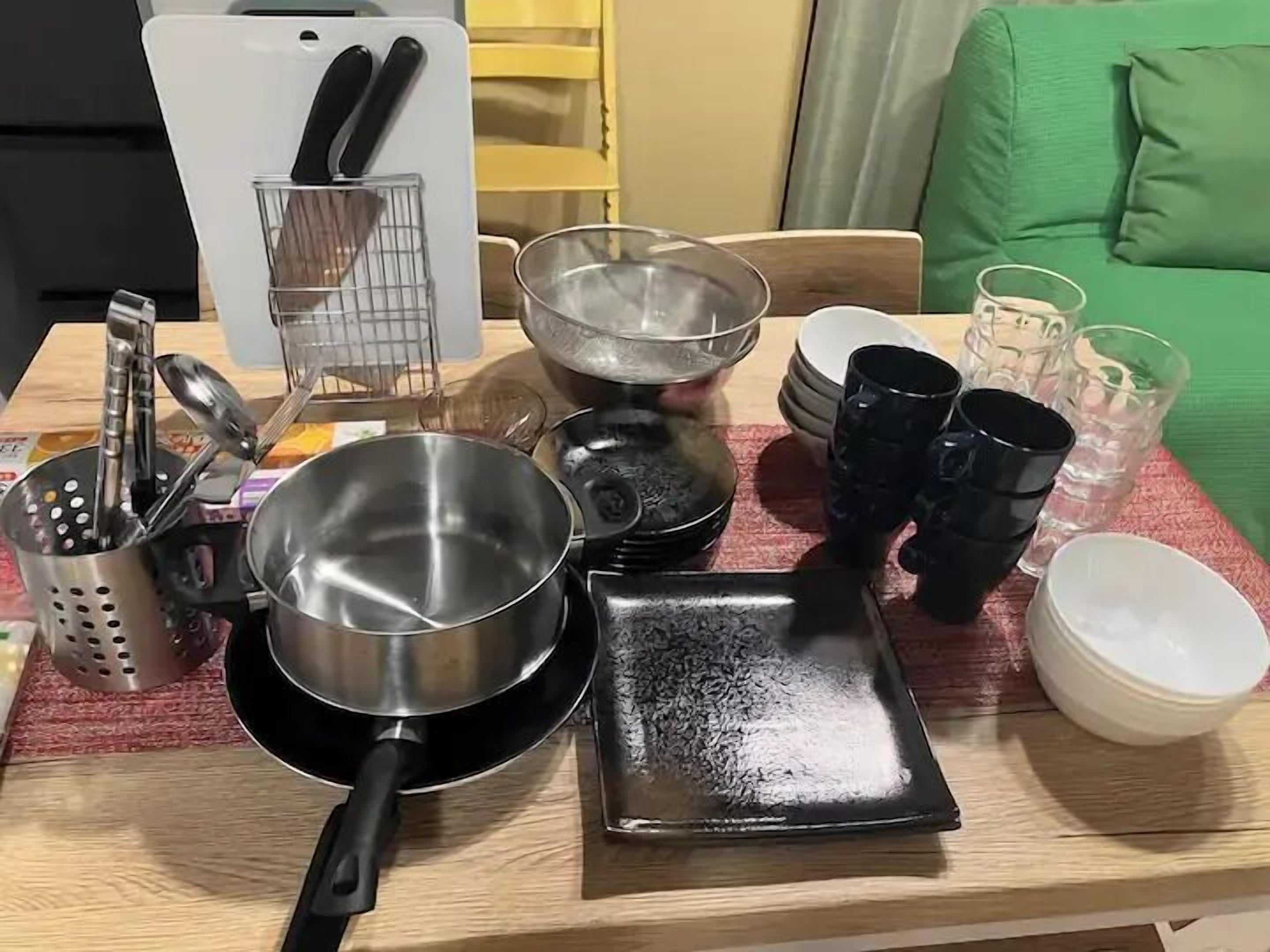 A kitchen counter with various cookware, including pots, pans, and a grater.
