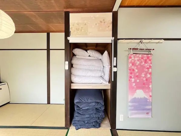 A traditional Japanese-style room with tatami flooring, a shoji screen, a bed with white bedding, and a pink floral tapestry on the wall. - Nakakasai Kodate (Tokyo)
