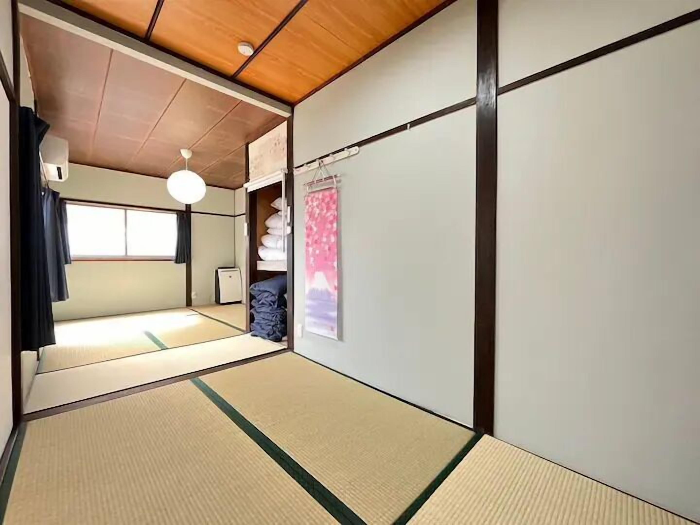 A traditional Japanese room with tatami flooring, a sliding door, a ceiling fan, and a small heater.