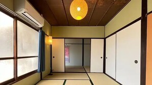 Une pièce de style japonais traditionnel, avec un sol recouvert de tatamis, des portes coulissantes et un luminaire au plafond.