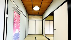 Une pièce de style japonais traditionnel, avec un sol recouvert de tatamis, des portes coulissantes et un luminaire au plafond.