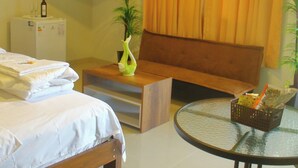Ein Hotelzimmer mit Bett, einer Sitzecke, Fernseher, kleinem Tisch und Stuhl.