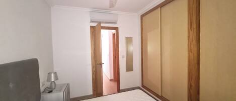 A bedroom with a bed, a bedside table, a ceiling fan, and a wardrobe.
