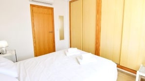 Una camera d'albergo con un letto, un armadio in legno e un comodino con una lampada.