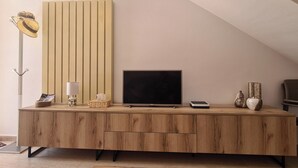 Un soggiorno moderno con un mobile TV in legno, una TV a schermo piatto, una lampada e oggetti decorativi.