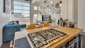 A modern kitchen with a gas stove, wooden table, and yellow chairs. - Modern Condo With Mountain Views, Walk To Downtown 2 Bedroom Condo (Salt Lake City)
