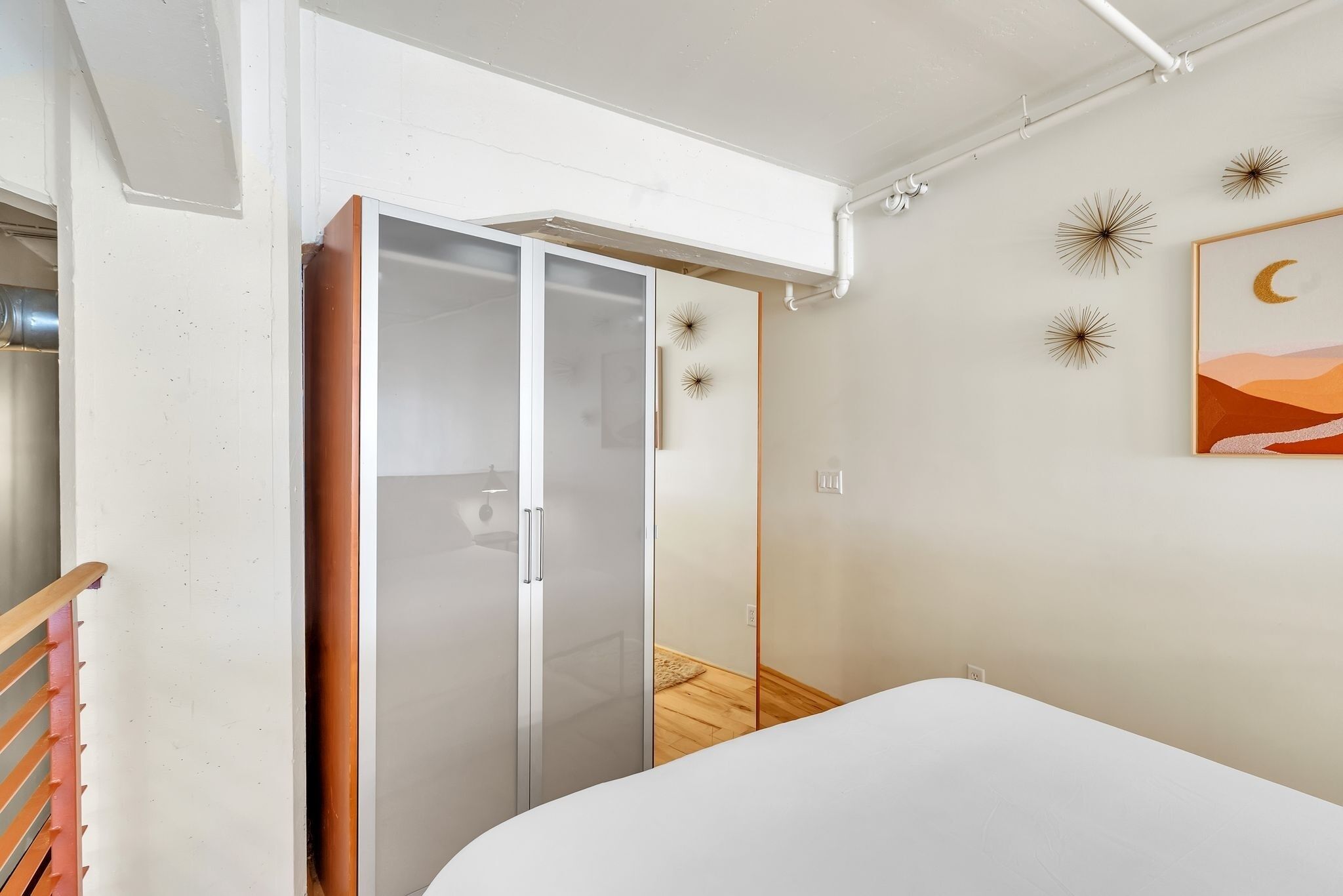 Ein Schlafzimmer mit Bett, Schiebetürenschrank und Wandgestaltung mit Sternen und Monden.