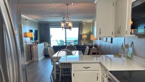 Une cuisine moderne avec un coin repas, un plancher en bois et une vue sur l’océan.