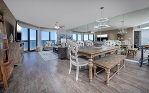 Relax in this spacious living area with a large dining table and bookshelf, offering a view of the outdoors.