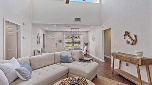 A spacious living room with a large sectional sofa, a wooden coffee table, and a dining area with a round table and chairs. - Mauna Loa Hideaway 3 Bedroom Home (Sarasota)