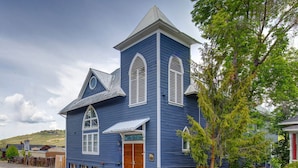 Una iglesia azul con un campanario blanco, puertas de madera y ventanas arqueadas.