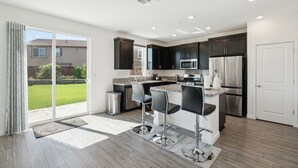 A modern kitchen with dark cabinets, stainless steel appliances, and a large island with bar stools. - Spacious 3br Home With Charming Backyard 3 Bedroom Home (Folsom)