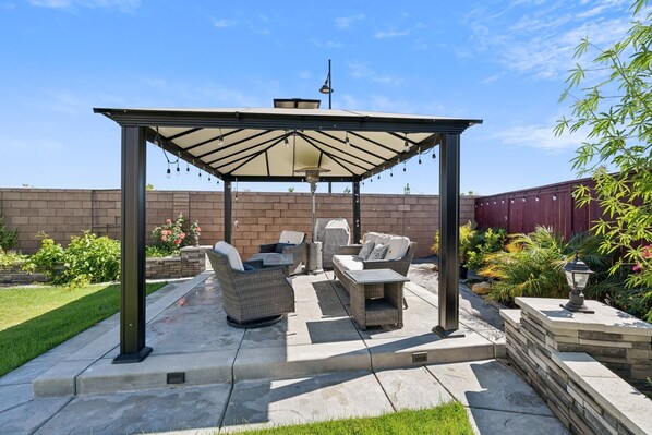 A covered patio area with outdoor furniture, a pergola, and a brick wall in the background. - Spacious 3br Home With Charming Backyard 3 Bedroom Home (Folsom)