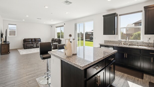 A modern kitchen with dark cabinetry, a granite countertop, and a large island. - Spacious 3br Home With Charming Backyard 3 Bedroom Home (Folsom)