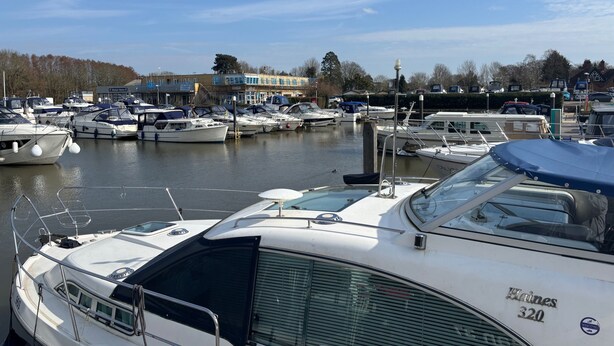 A marina with multiple boats docked, a clear sky, and buildings in the background. - Riverside Boat Retreat on the River Thames (Windsor)