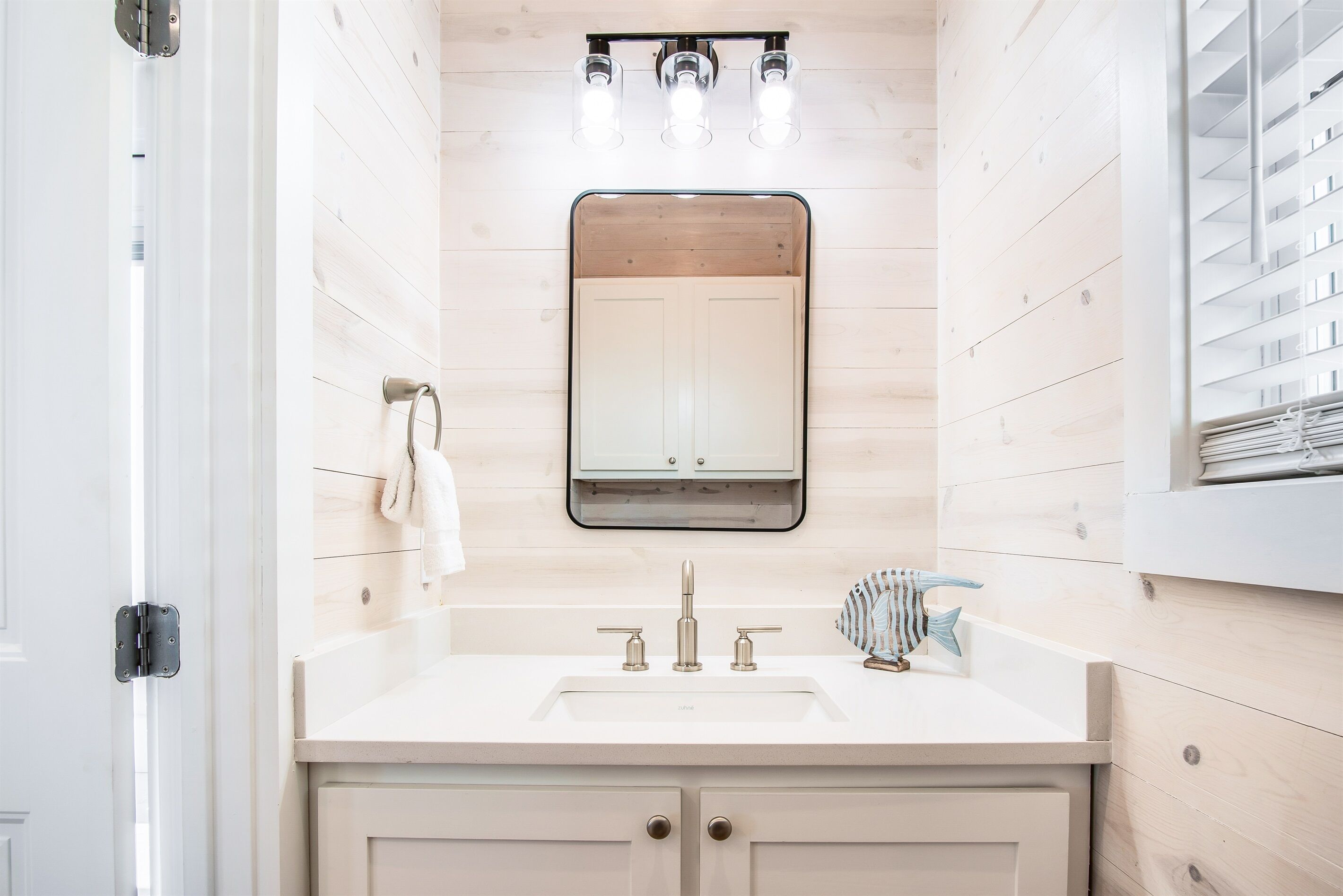 A bathroom with a white sink, two faucets, a mirror, and a towel rack.